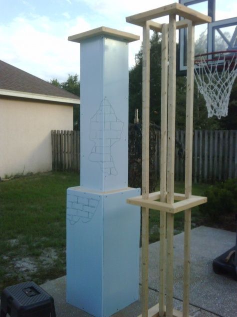 a basketball hoop is in front of a tall blue sculpture with an arrow drawn on it's side