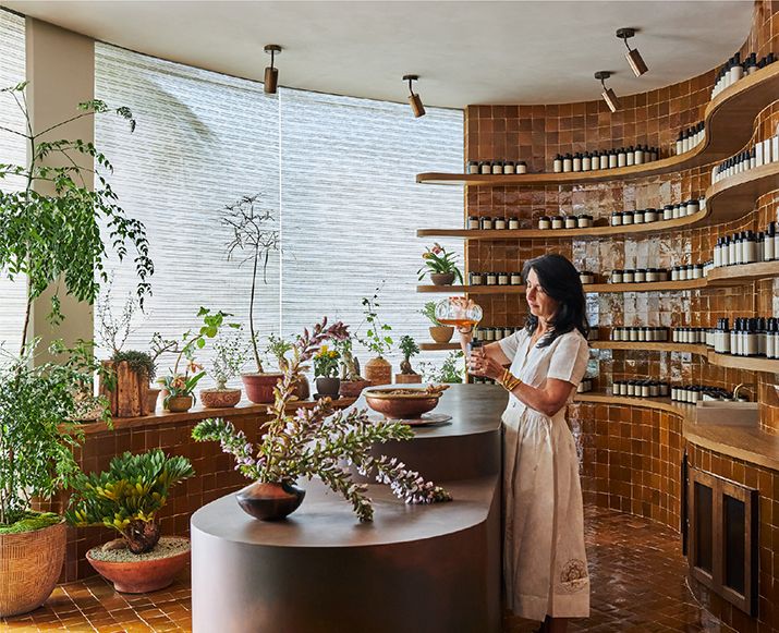 a woman standing in front of a counter filled with plants