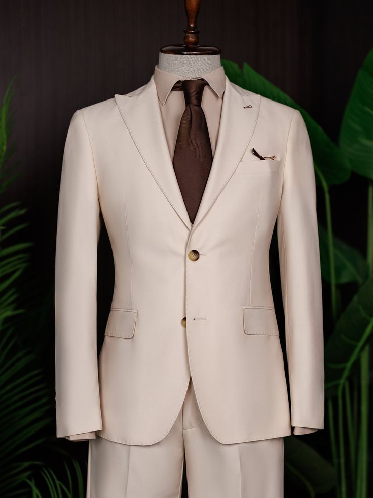 Color: beige Material: 73% polyester, 23% viscose, 4% elastane Suit includes blazer, waistcoat, & trousers Single-breasted suit (2-button blazer) Lapel type: peak lapels Jacket interior lining option: fully-lined Jacket vent: double vent Fitting: modern-fit Care instructions: dry clean only Machine washable: no Luxury Single-button Sets With Notch Lapel, Beige Tuxedo Set With Notch Lapel, Beige Tuxedo Set For Business, Elegant Beige Double Breasted Suit For Formal Events, Elegant Beige Tuxedo With Notch Lapel, Elegant Cream Double Breasted Suit With Suit Collar, Beige Fitted Tuxedo Set, Slim Fit Single-breasted Three-piece Suit, Cream Single Breasted Blazer With Notch Lapel