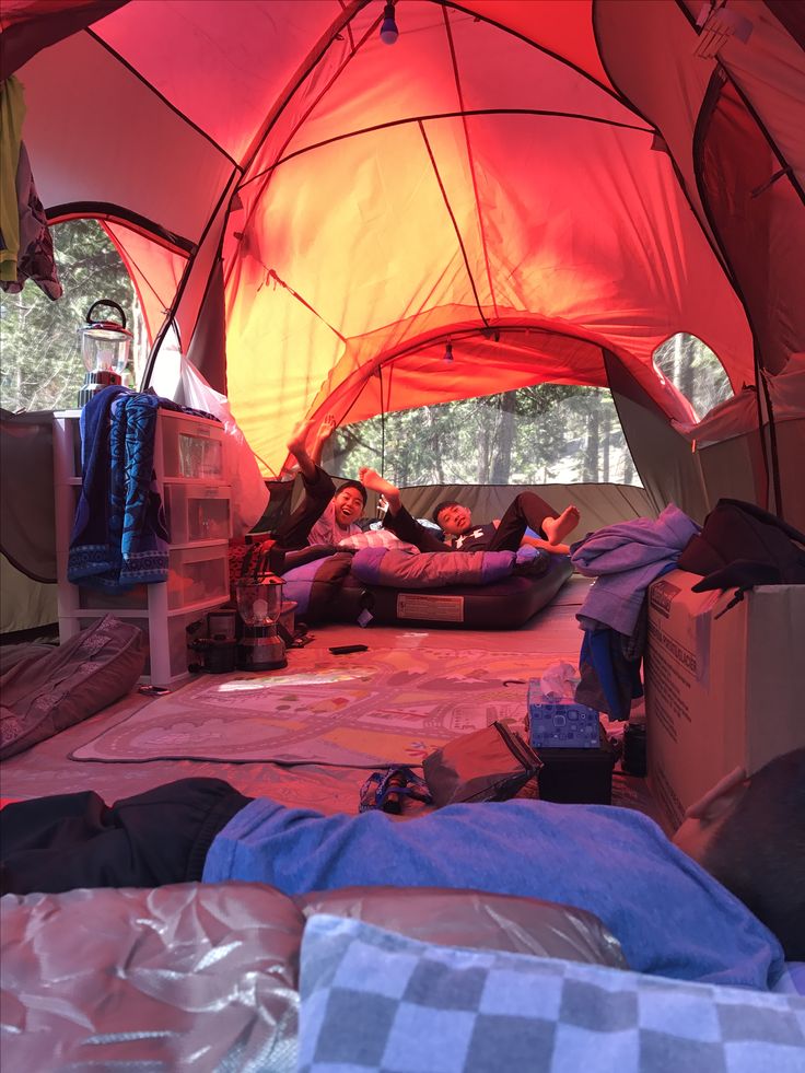 two people laying on the ground in a tent with sleeping bags and blankets around them