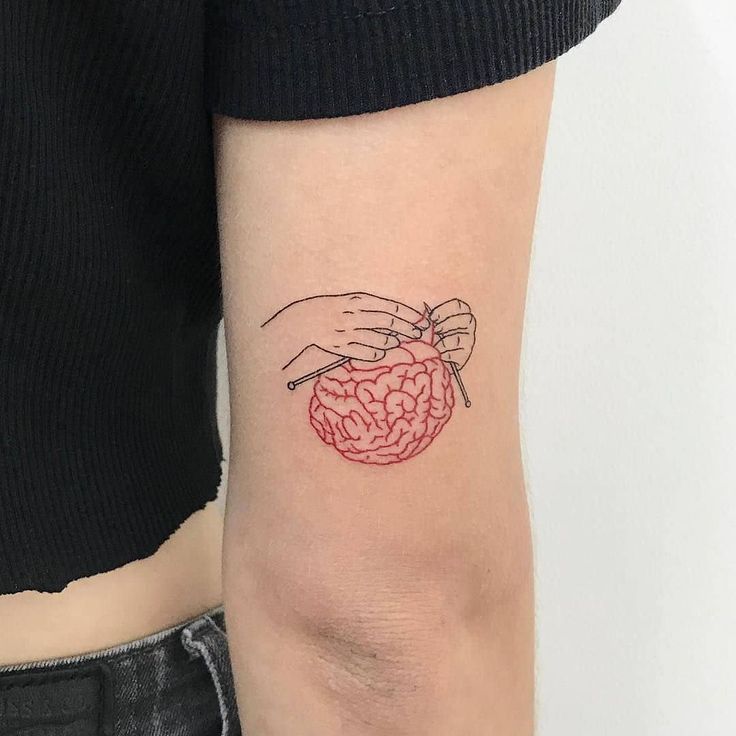 a small tattoo on the arm of a woman's left hand holding a brain