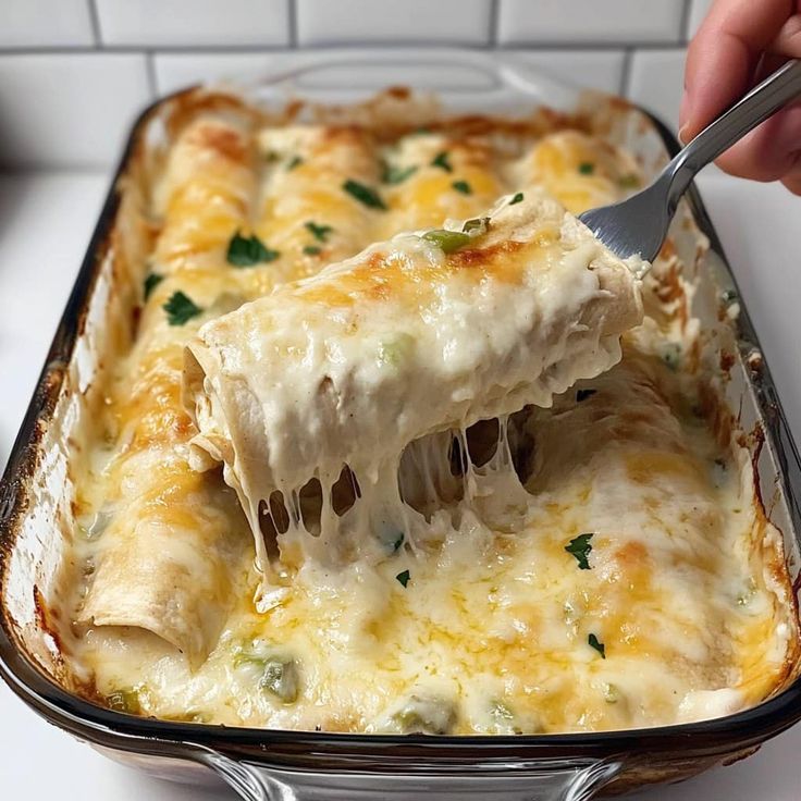 a person holding a spatula over a casserole dish filled with lasagna