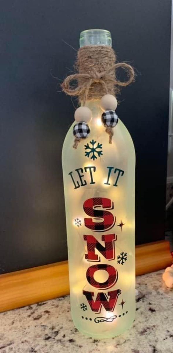 a lighted bottle that says let't it snow on the front and side with lights in the bottom