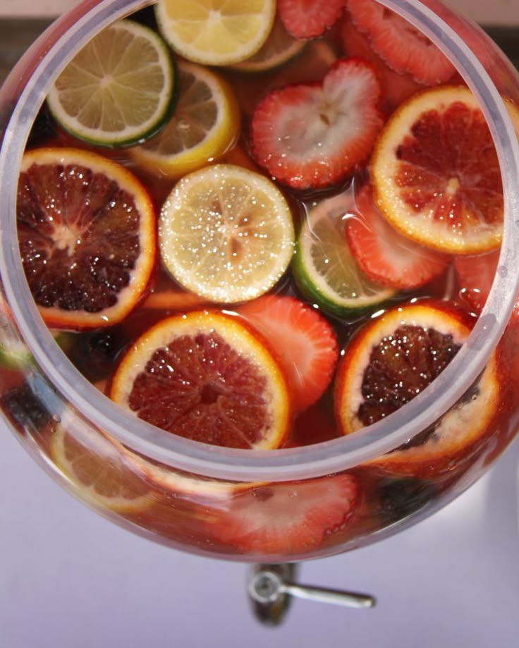 a pitcher filled with fruit and water on top of a table