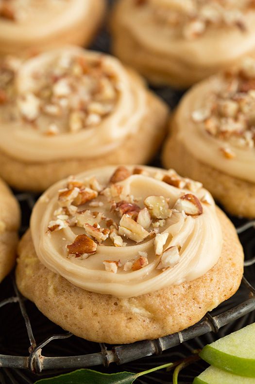 several cookies with white frosting and nuts on top sitting on a cooling rack together