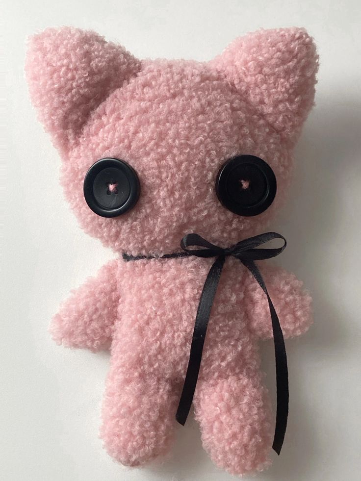 a pink teddy bear with big eyes and a black ribbon around it's neck