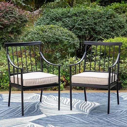 two black chairs sitting on top of a blue and white patterned rug next to bushes