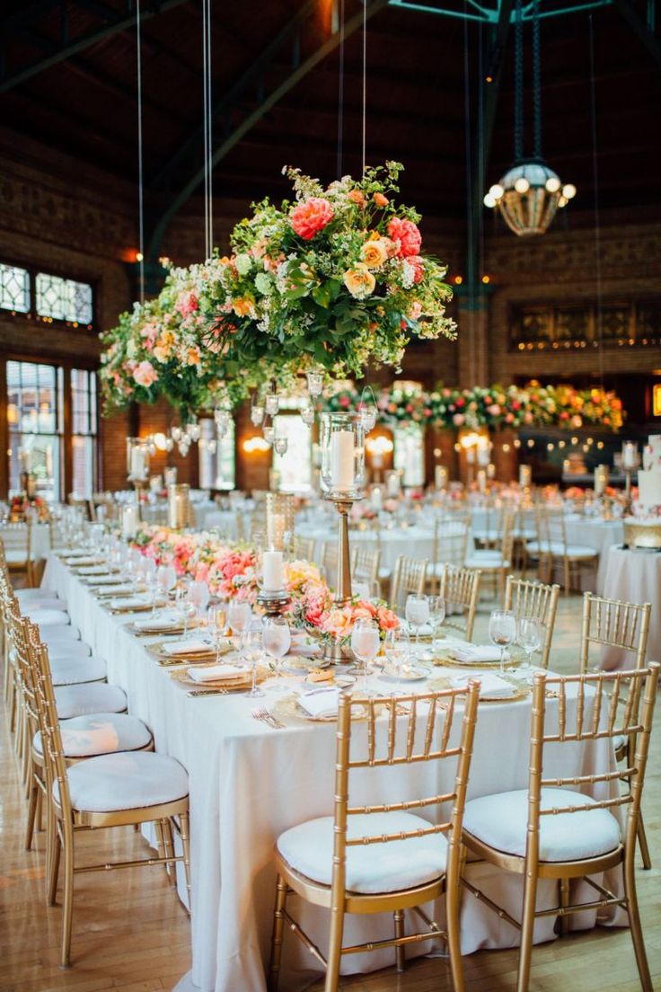 the tables are set up with white linens and flowers in tall centerpieces