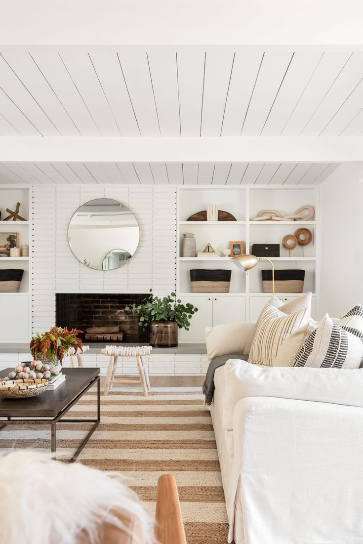 a living room filled with furniture and a fire place next to a wall mounted mirror