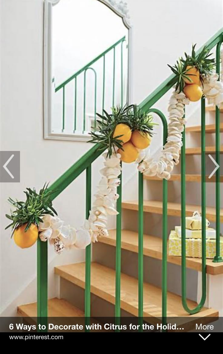 some oranges are hanging on the banister with white flowers and greenery around them