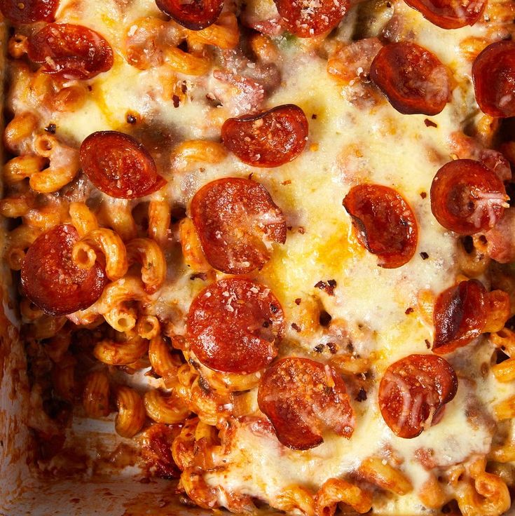 a pizza with pepperoni and macaroni in a white casserole dish