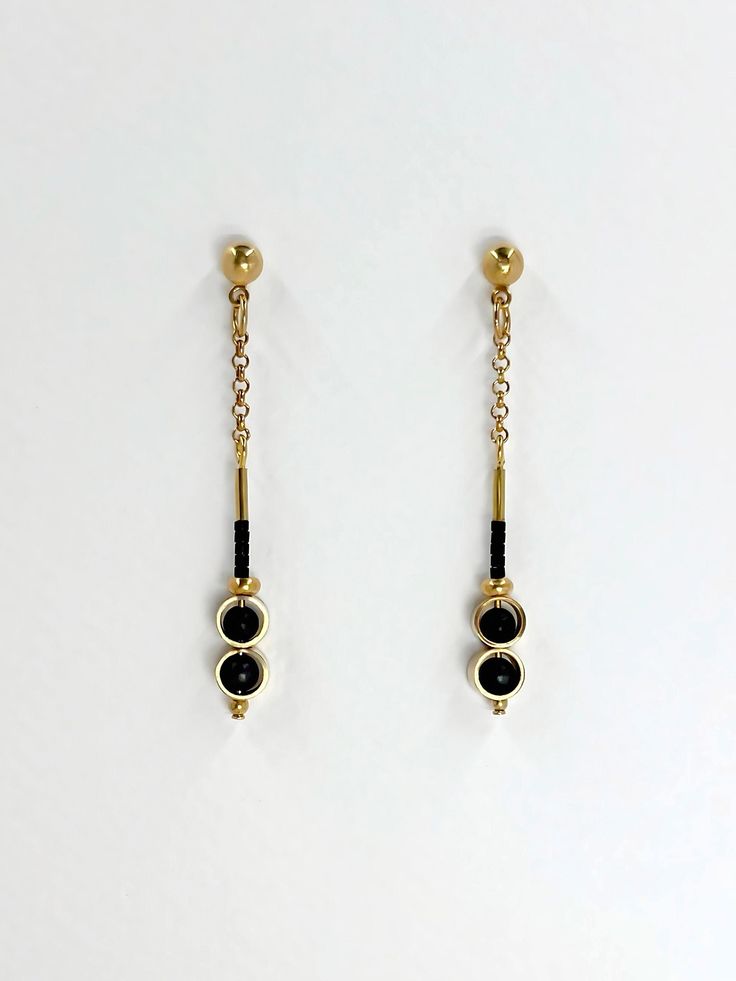 These earrings are dainty and minimalistic but detailed! Thick, straight cut, golden brass rings encircle each semi precious stone of matte black onyx, complimentary tiny, matte black glass seed beads sit above.  The shiny warm, golden brass contrasts beautifully with the deep black stone.  The simplicity and geometric shapes create a contemporary design.  A solid brass ball stud with stainless steel earring post sits at the top.  Approximate measurements- 5.5 cms long 0.75 cm wide All Set Theor Nickel Free Minimalist 14k Gold Filled Earrings, Minimalist Metal Linear Earrings With Adjustable Chain, Minimalist Yellow Gold Drop Plug Earrings, Minimalist Gold Plated Earrings, Black Dainty Metal Jewelry, Dainty Black Metal Jewelry, Minimalist Black Single Plug Earring, Minimalist Brass Jewelry With Matching Earrings, Minimalist Gold Plated Drop Earrings