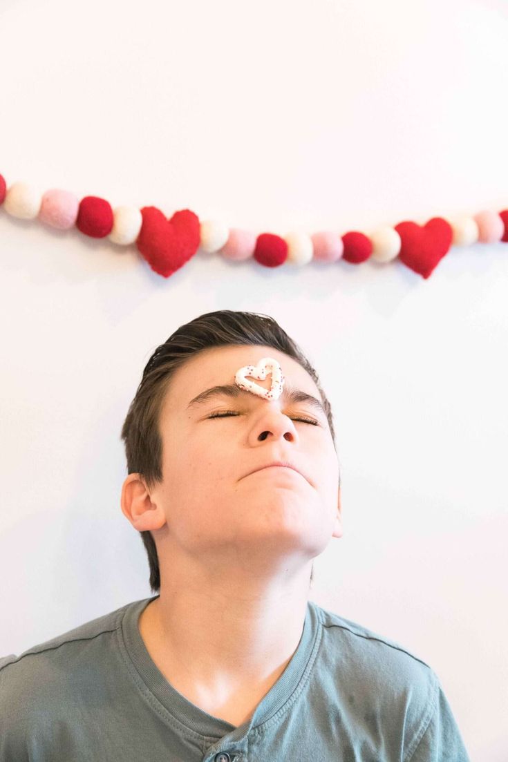 a young boy with his eyes closed looking up at a string of red and white hearts