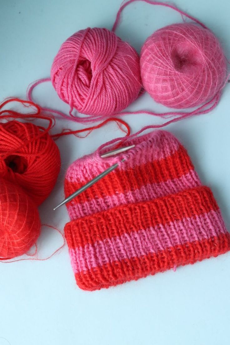 two balls of yarn are next to a pair of knitting needles and a ball of yarn