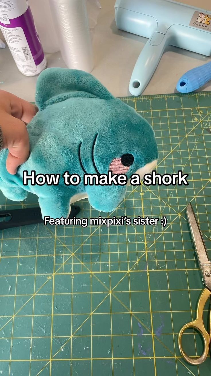 someone is making a shark stuffed animal out of a blue teddy bear with scissors next to it