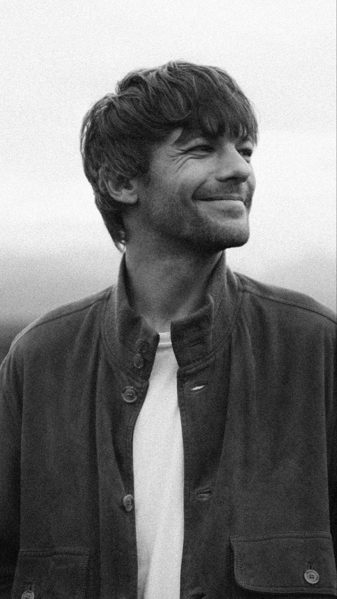 a black and white photo of a man with a smile on his face, looking to the side