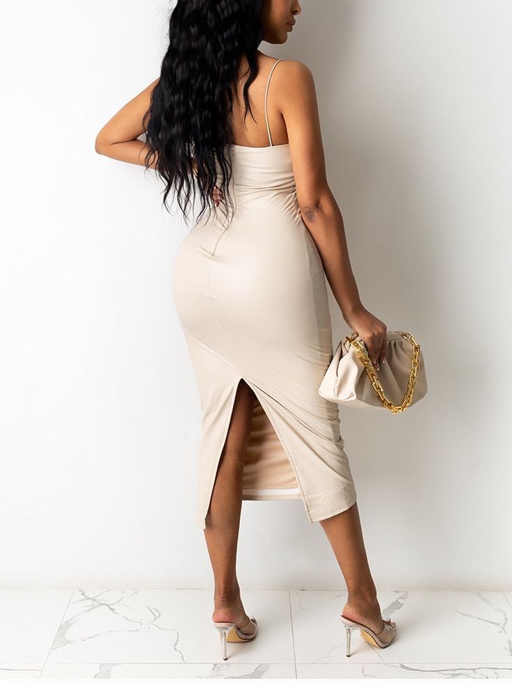 a woman in a beige dress is holding a purse