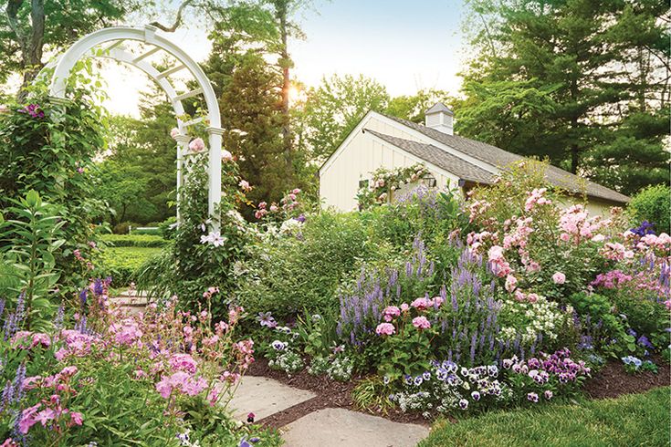 the garden is full of colorful flowers and greenery, including an arch in the center