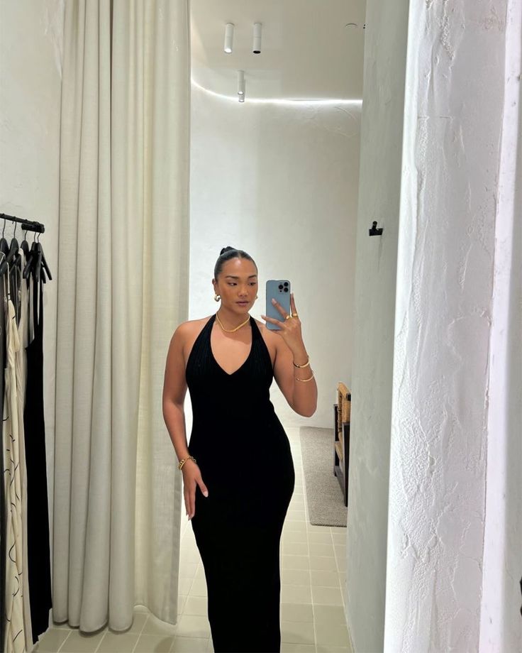 a woman in a black dress taking a selfie