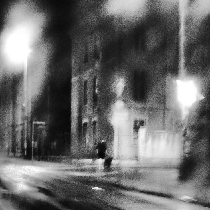 blurry photograph of people walking down the street at night with buildings in the background