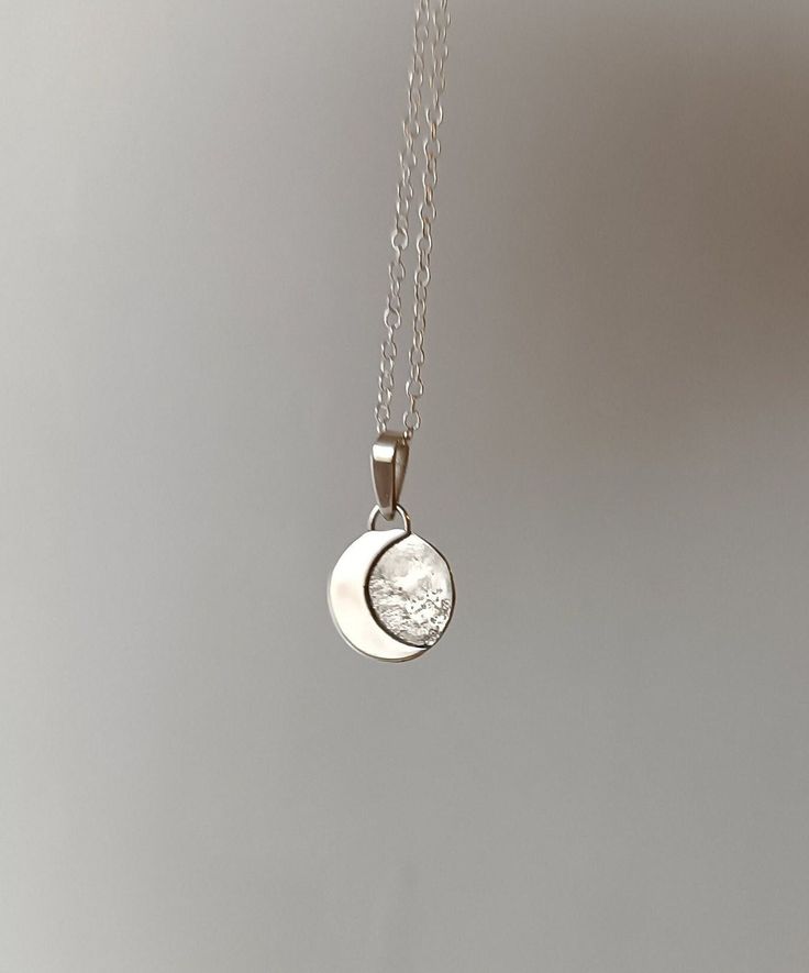 This sterling silver pendant with a crescent moon is a unique, handmade piece. Each moon has its own special shape, so no two are alike. If you prefer a specific position for the moon, please let me know. Additionally, the silver chain is adjustable, allowing you to wear it at your preferred length between 40 and 45 cm. It's the perfect accessory to add a special touch to your unique style. We use the highest quality silver, ethically sourced from European mines, to make this pendant. Made in Barcelona ---If you have any questions, write to me and I will be happy to assist you.---" Minimalist Moon Phase Pendant Necklace, Handmade Crescent Sterling Silver Jewelry, Dainty White Gold Moon Charm Jewelry, Moon Phase Pendant Necklaces For Anniversary, Sterling Silver Moon-shaped Jewelry For Anniversary, Minimalist Moon Phase Round Pendant Jewelry, Sterling Silver Moon Charm Necklace For Anniversary, Sterling Silver Necklaces With Moon Charm For Anniversary, Silver Half Moon Jewelry Engraved