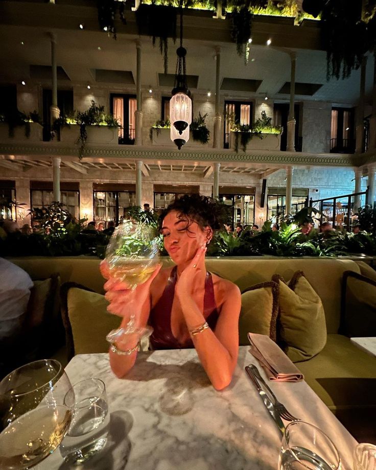 a woman sitting at a table with a glass of wine