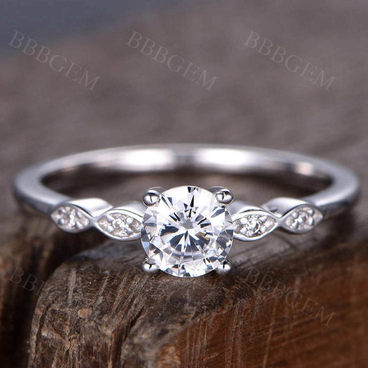 a white gold engagement ring with leaves on the band and a round diamond center stone