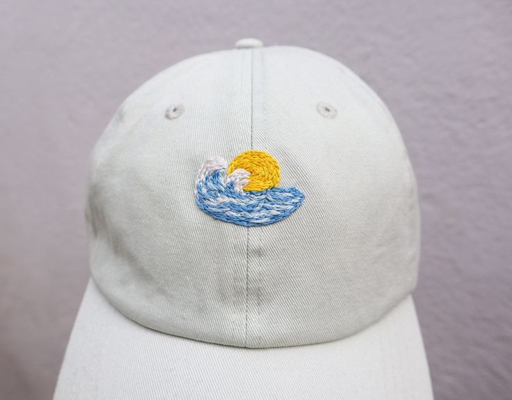 Hand Embroidered Light Blue,wave and sun hat. The perfect addition to your Spring/Summer wardrobe this season, every design is hand drawn and hand embroidered onto the hat meaning that each one is individually unique. 🌿 Perfect for everyday wear or makes a great gift. 🌿 One size fits all with an adjustable buckle on the back. 🌿 The cap is 100% cotton embroidered with cotton thread. 🌿 Care instructions - Hand wash warm 30oC. ** Please note that hat colours may differ slightly due to the lighting on the images ** If you would like additional details such as any measurements, or further customisation please don't hesitate to contact me. Other hats are available in my Etsy shop. Surfer Hat, Embroidered Hats Ideas, Hats Ideas, Hat For Summer, Embroidery Hat, Basic Hand Embroidery Stitches, Fiber Crafts, Festival Hat, Embroidered Cap