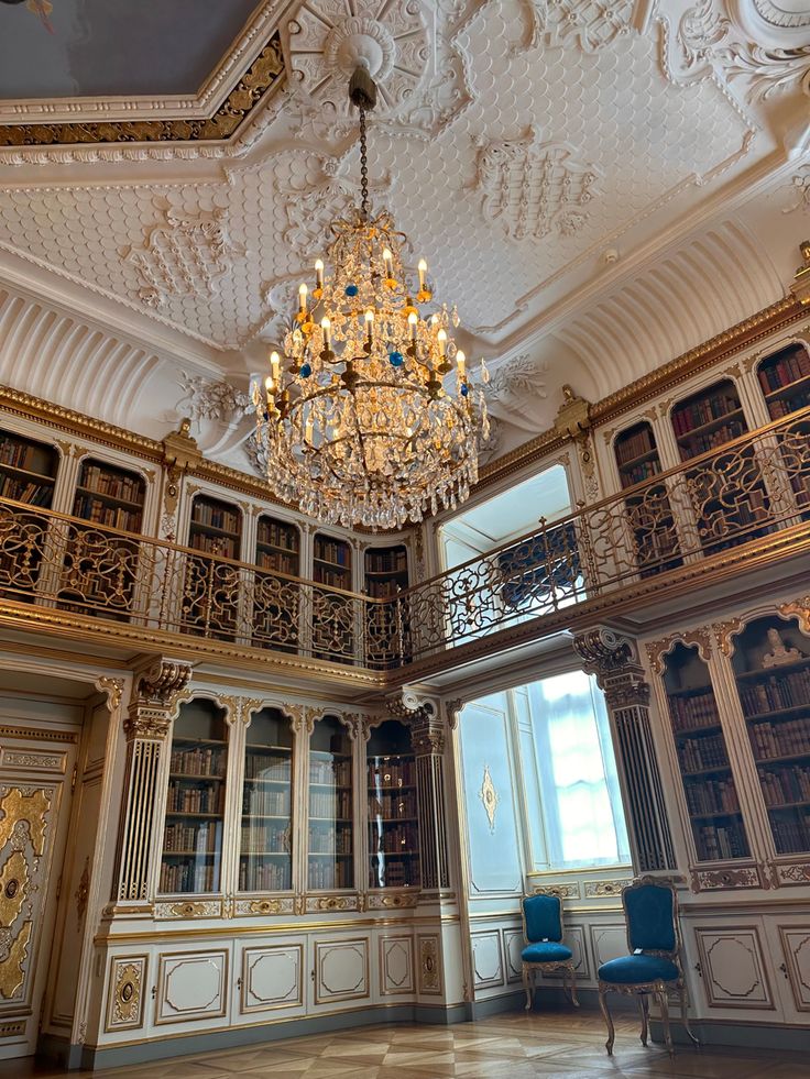 a chandelier hangs from the ceiling in an ornately decorated room with bookshelves