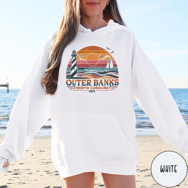 Celebrate the beauty of North Carolina's beautiful islands and coastline with our OBX Outer Banks Hoodie from Triangle Threads. This crewneck celebrates the beauty of the Cape Hatteras Lighthouse and the pristine sand dunes of the Outer Banks. Perfect for an OBX lover, or to remind you of that awesome summer vacation, this Gildan 18500 50/50 blend hooded sweatshirt comes in all sizes big and small for oversize and regular fits. So grab one today and celebrate the Carolina Coast and the beauty of Long Sleeve Hoodie For Beach In Fall, Casual Hoodie For Beach In Fall, Casual Beach Hoodie For Fall, Casual Fall Beach Hoodie, Hooded Hoodie For Vacation In Winter, White Hooded Hoodie For Beach Season, Long Sleeve Hoodie For Beach Vacation, Hooded Hoodie For Winter Vacation, Hooded Winter Hoodie For Vacation