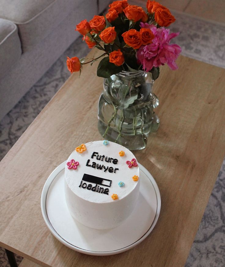 a white cake sitting on top of a table next to a vase filled with flowers