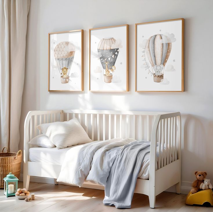 three framed hot air balloons hang above a white crib