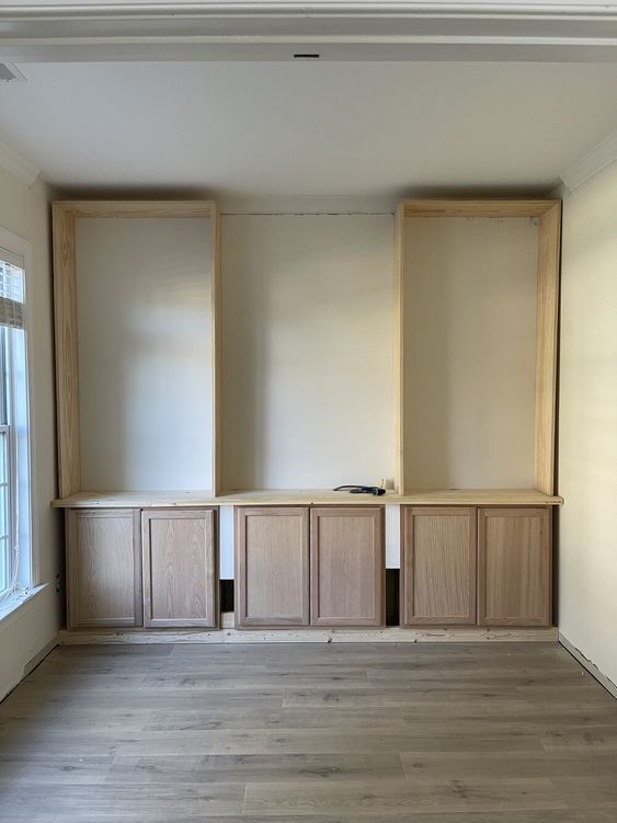 an empty room with wooden cabinets in the middle and hard wood flooring on the other side