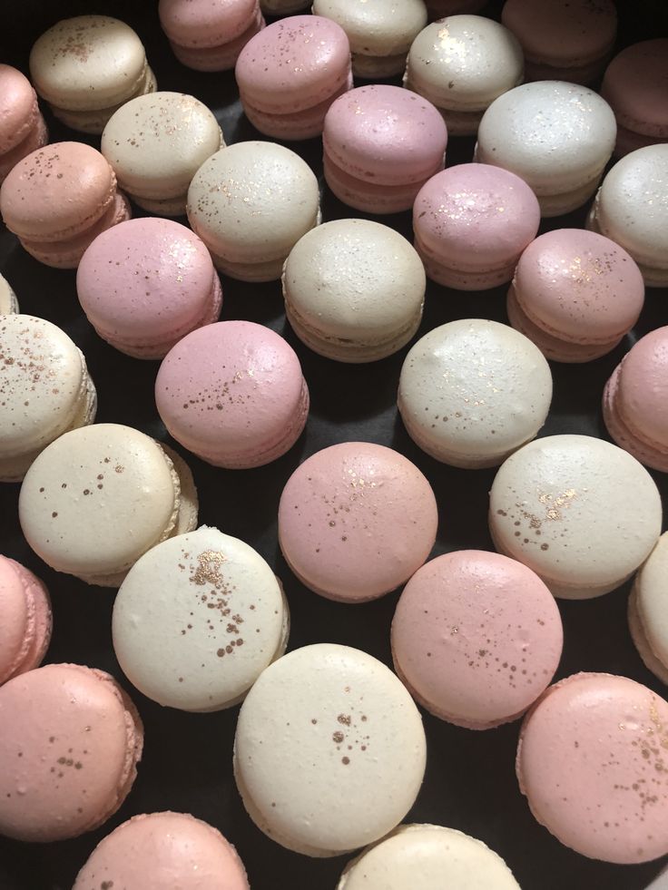 there are many pink and white macaroons in the pan