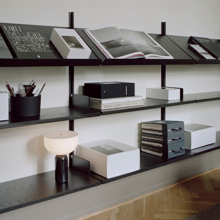 the shelves are filled with books and other office supplies in black, white, and grey colors