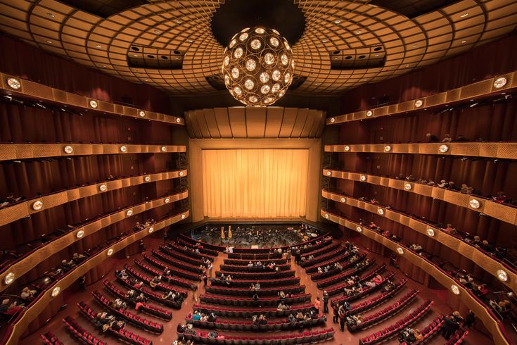 an auditorium with rows of seats and chandelier hanging from the ceiling, looking down at the stage