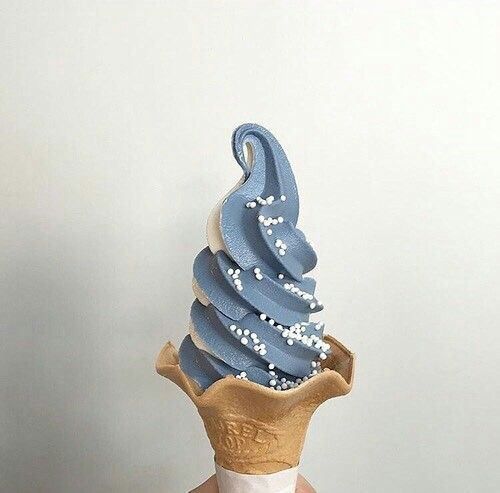 an ice cream cone with blue icing and white sprinkles on top