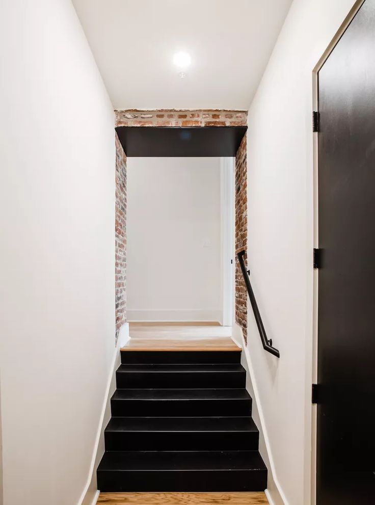 an empty hallway with black steps leading up to the door