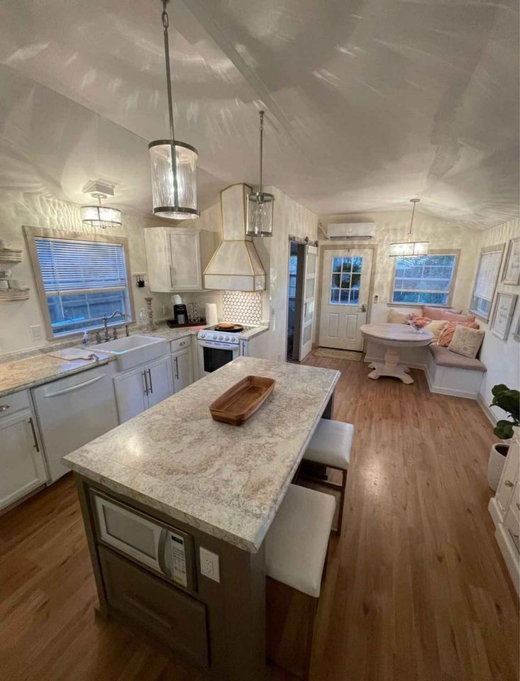 a large kitchen with white cabinets and wood flooring, along with an island in the middle