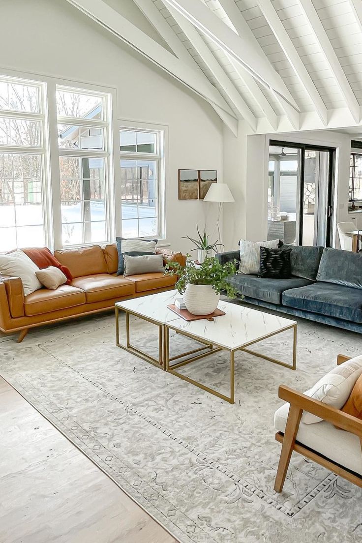 a living room with couches, chairs, tables and windows in the ceiling area