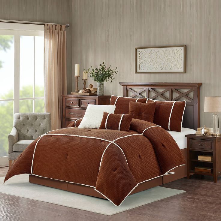 a bed with brown and white comforters in a bedroom next to a window,