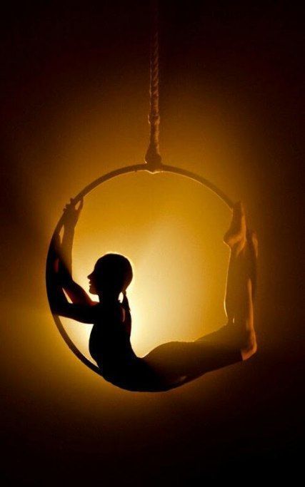 a woman sitting in a circle swing with the light shining on her face behind her