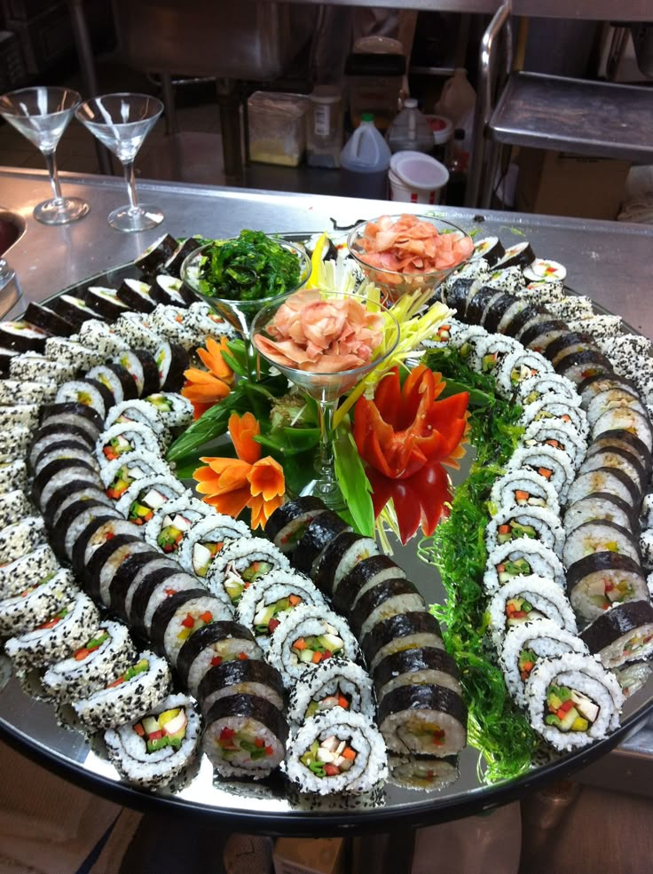 an assortment of sushi on a platter with flowers and garnishes