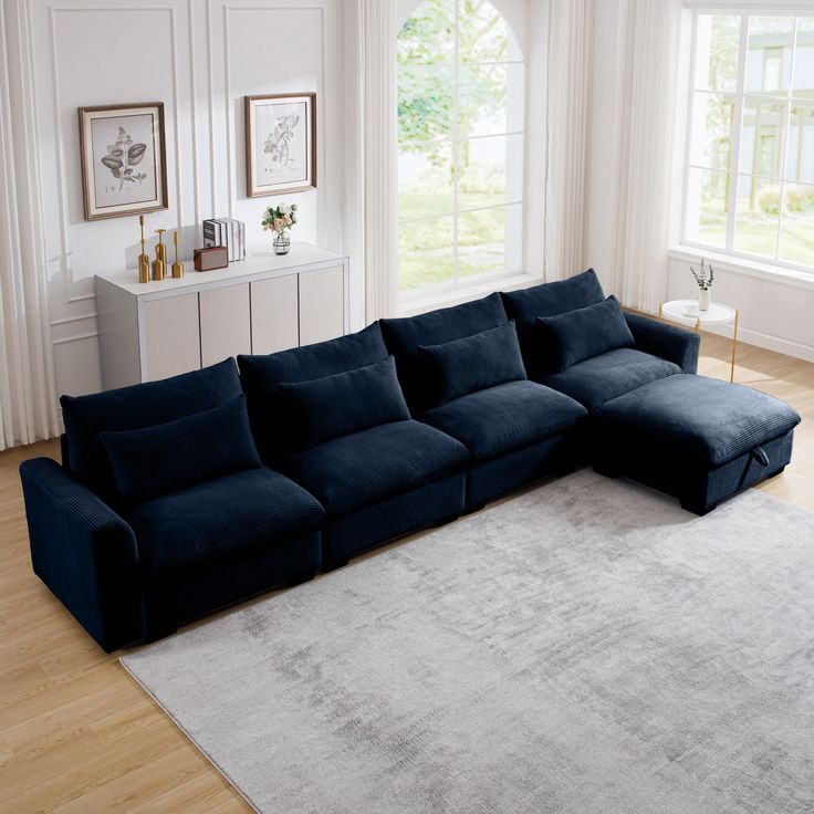 a living room with a large blue sectional couch and white rug on the hardwood floor