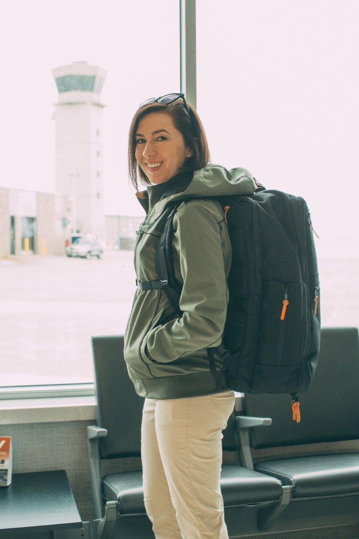 a woman standing in an airport with a backpack on her back