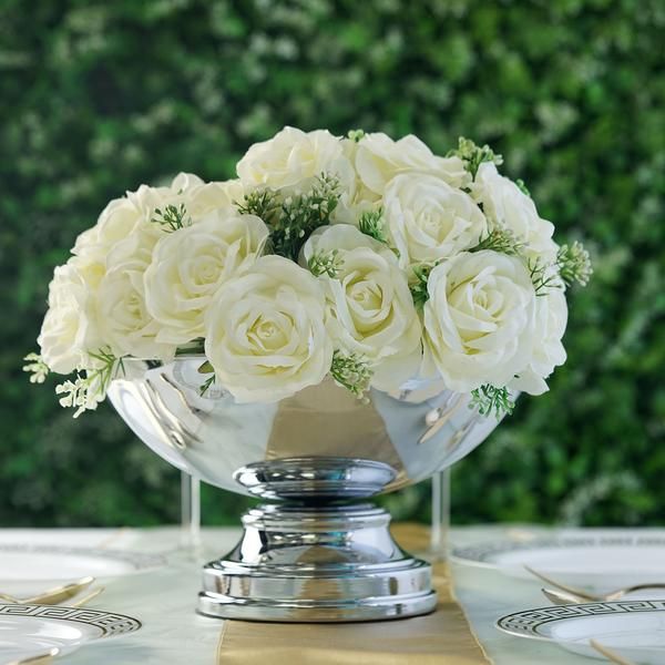 a vase filled with white flowers sitting on top of a gold plated centerpiece