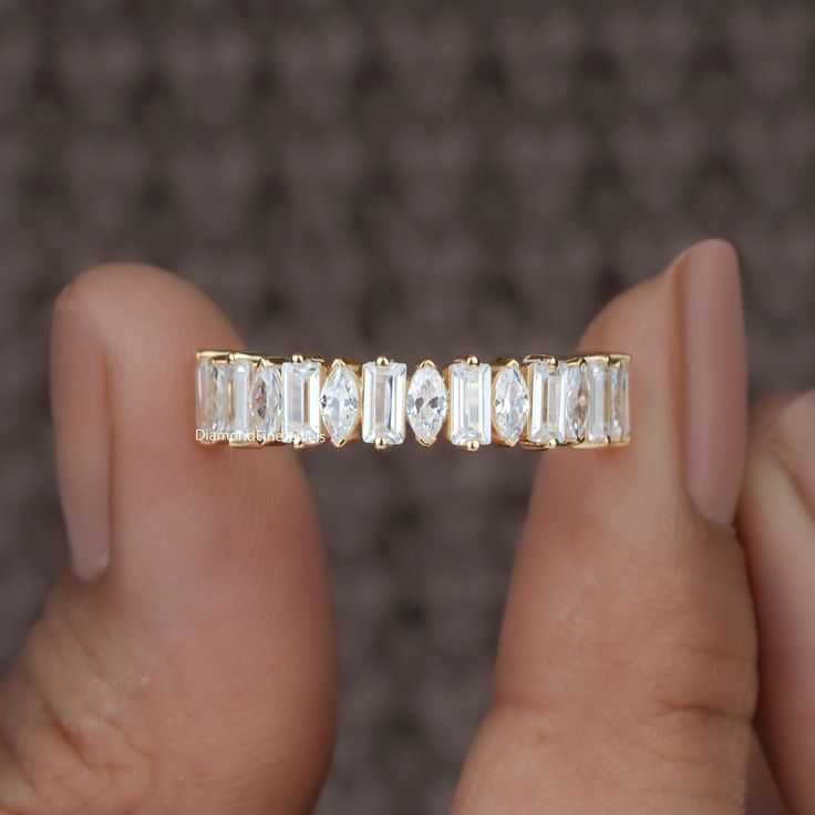 a woman's hand holding a gold ring with three baguettes on it