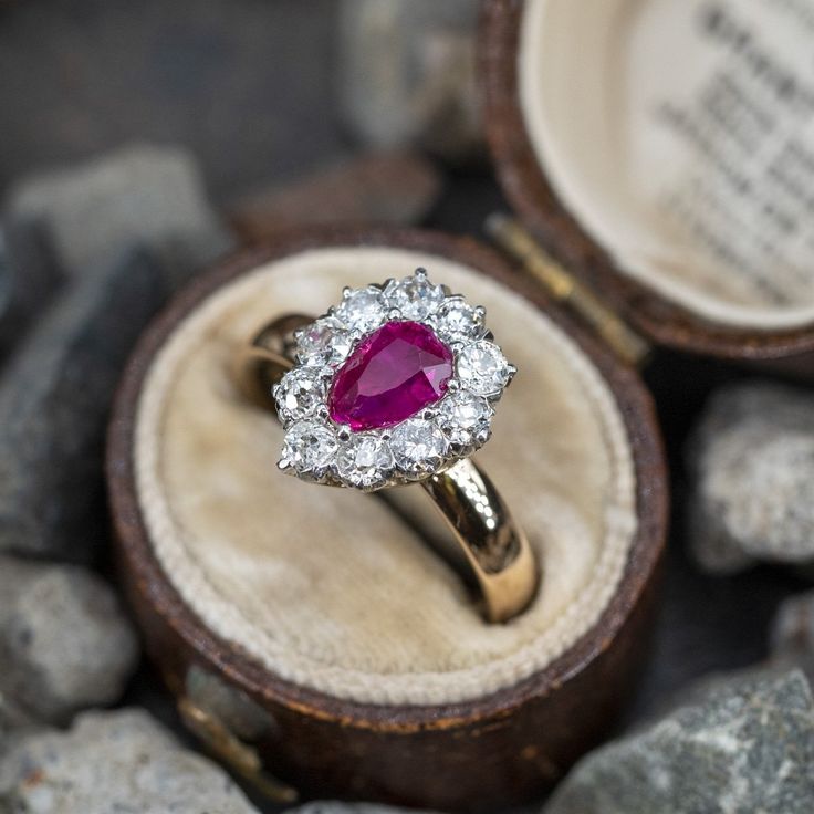 This beautiful engagement ring is centered with one (1), prong set, pear cut natural ruby and bordered with ten (10), prong set, old European/brilliant cut diamonds. The ring measures 13.2mm at the top, rises 6.2mm above the finger, tapering to 3.3mm wide and 1.8mm thick at the base of the shank. This ring is currently a size 6.5. The ruby shows light chips/abrasion as well as many surface reaching inclusions. The diamond at the tip is chipped on one edge. Beautiful Engagement Ring, Ruby Engagement Ring, Beautiful Engagement Rings, Natural Ruby, October Birth Stone, Diamond Halo, Pear Cut, High Quality Jewelry, Brilliant Cut Diamond