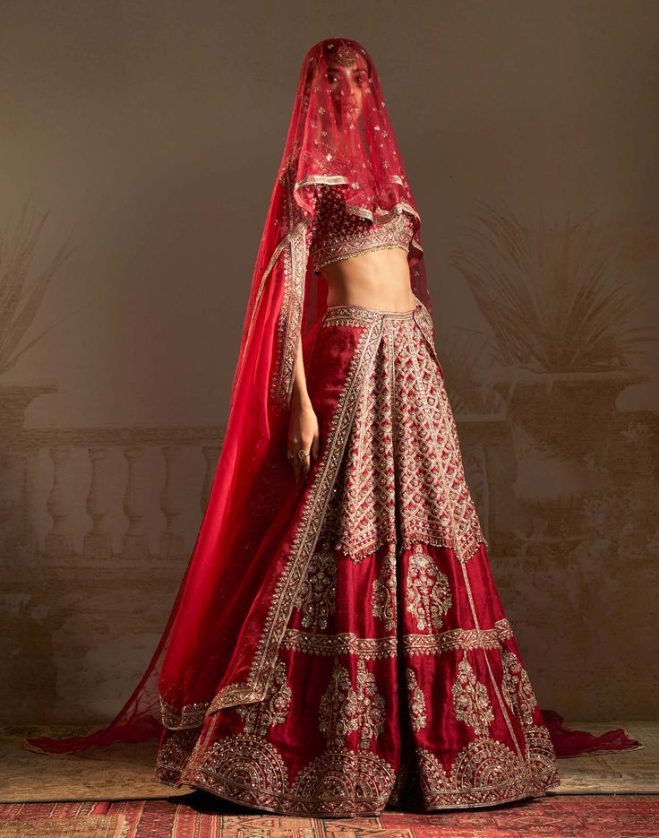 Step into a world where the whispers of persian culture meet the vibrant hues of love with our red geometric jewelled lehenga set. This enchanting ensemble, adorned with intricate tree motifs symbolizing a bride's transformative journey, features a stunning red lehenga, a matching blouse, and a luxurious dupatta with scalloped edges. The timeless red hue, embodying tradition and prosperity, takes center stage, radiating passion and fortune. Red Palazzo Set With Intricate Embroidery And Traditional Drape, Red Palazzo Set With Intricate Embroidery, Elegant Red Palazzo Set With Intricate Embroidery, Red Embroidered Palazzo Set For Festivals, Designer Red Palazzo Set With Intricate Embroidery, Designer Red Embroidered Palazzo Set, Red Designer Wear Sets With Traditional Drape, Red Traditional Drape Sets For Designer Wear, Red Festive Sets For Reception