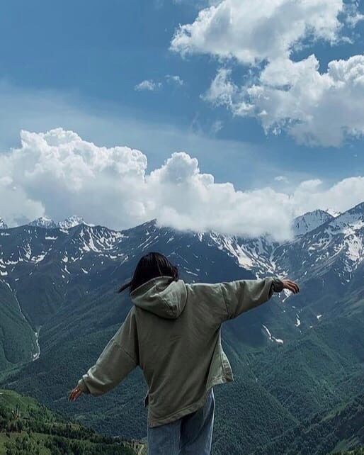 a person standing on top of a mountain with their arms spread out in the air